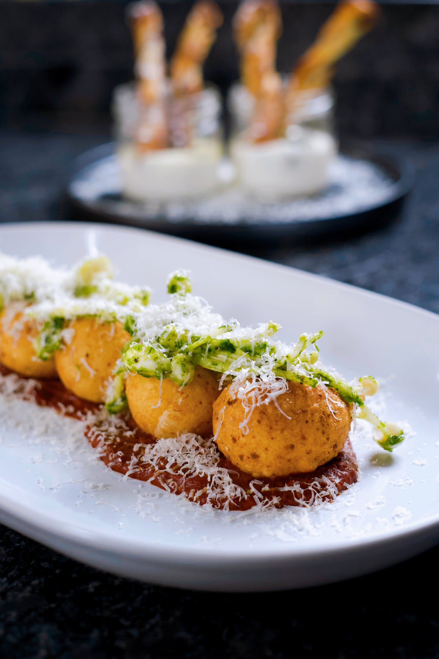 Beignets de parmesan, coulis de tomates rôties, salade de champignons enoki au pesto de roquette et pistaches torréfiées