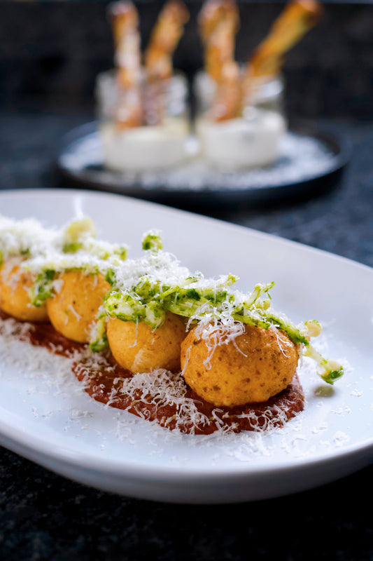 Beignets de parmesan, coulis de tomates rôties, salade de champignons enoki au pesto de roquette et pistaches torréfiées