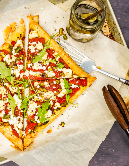 Tarte fine aux poivrons confits, pesto de roquette aux pistaches, miel et neige de feta