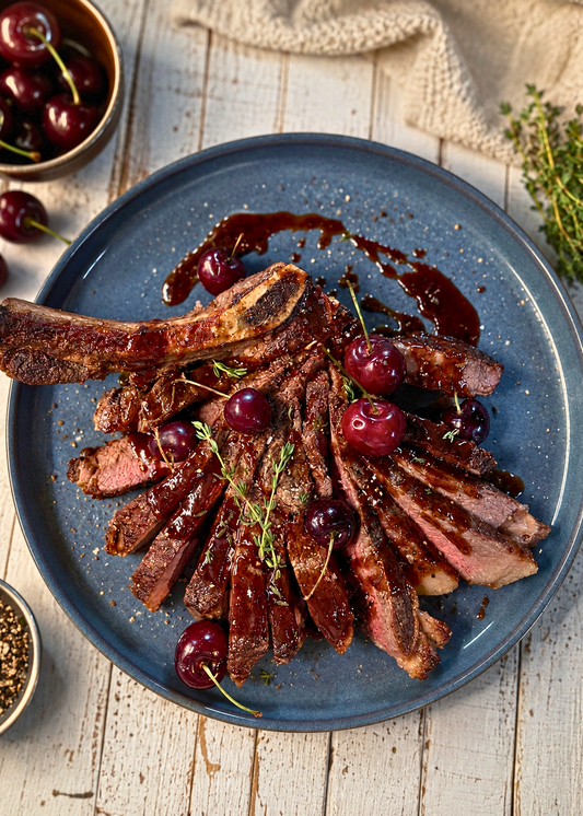 Contrefilet grillé, sauce aux cerises rouges, ail noir et poivre noir