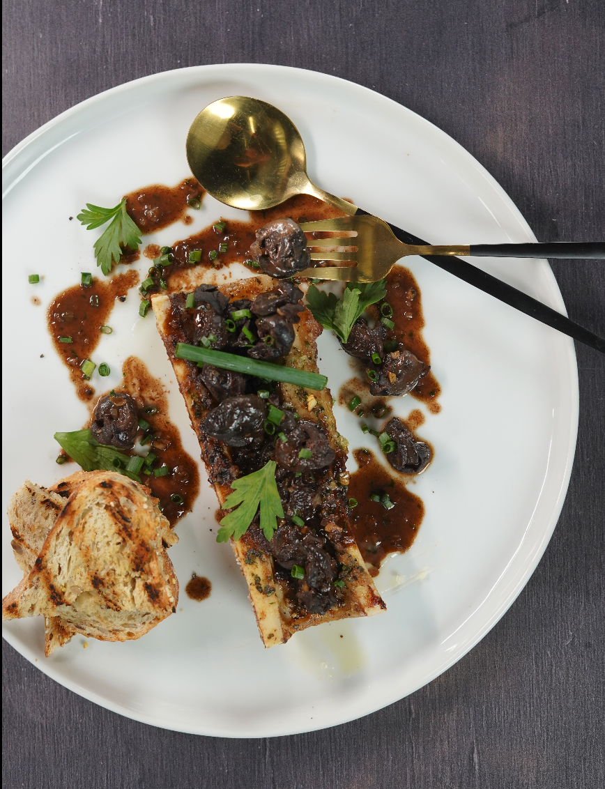 Escargots à la bourguignonne, vin rouge et jus corsé, servis sur os à moelle rôti