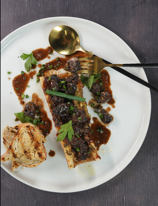 Escargots à la bourguignonne, vin rouge et jus corsé, servis sur os à moelle rôti